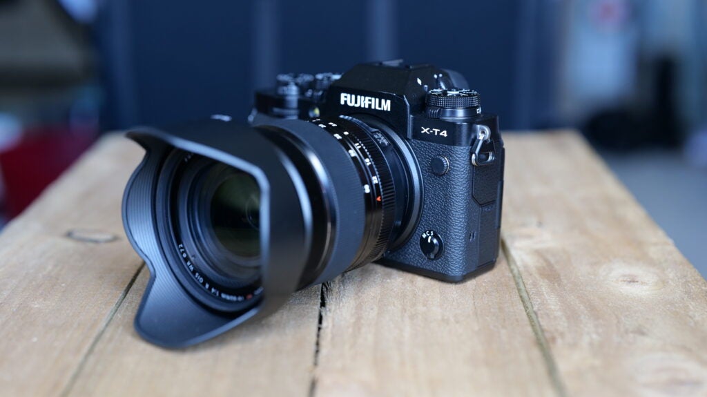 Rechtwinklige Ansicht einer schwarzen Fujifilm XT4-Kamera, die auf einem Holztisch steht, Vorderansicht