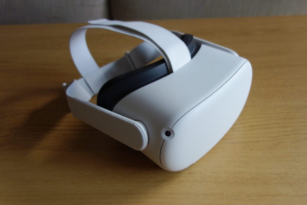 Eine weiße Oculus Quest 2 auf einem Holztisch, Ansicht von hinten links