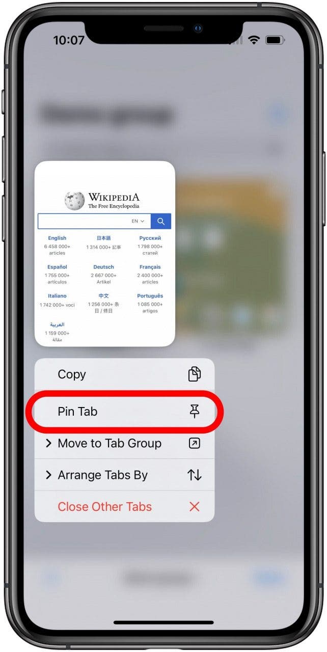 Safari-App mit dem Registerkartenbildschirm für eine Registerkartengruppe, die im Hintergrund verschwommen ist, und einer einzelnen Registerkarte, die mit dem darunter geöffneten Menü für langes Drücken sichtbar ist.  Die Option Pin Tab ist im Menü markiert.