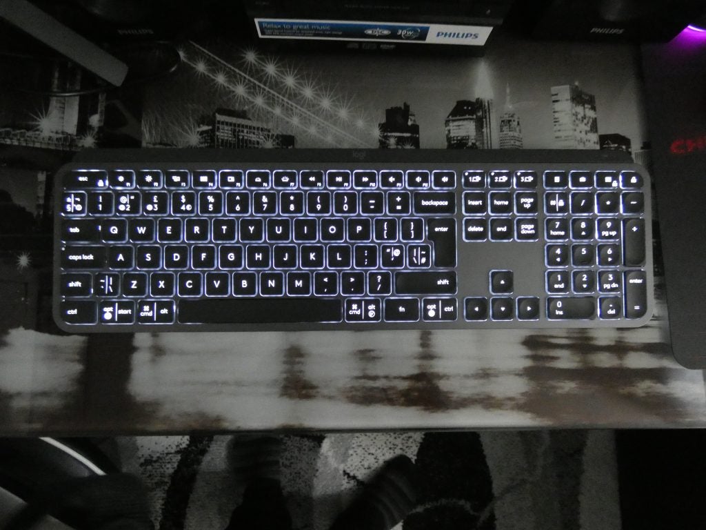 Blick von oben auf eine schwarze Logitech MX-Tastatur, die auf einem Tisch mit Lichtern unter den Tasten liegt