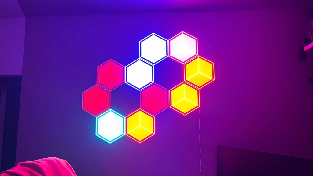 10 Govee Glide Hexagon Light Panels Ultra, die individuell angepasst werden können, um verschiedene Farben bei unterschiedlichen Helligkeitsstufen anzuzeigen. 