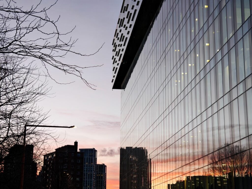 Reflexion des städtischen Sonnenuntergangs an der Glasfassade eines modernen Gebäudes.